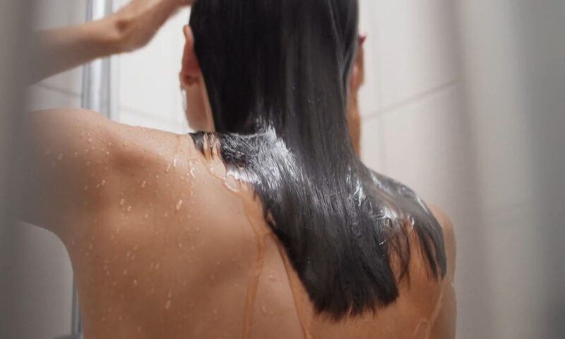 devojka pere kosu pod tušem