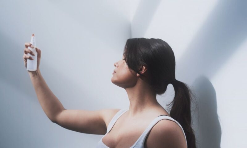 devojka sa zalizanim repom prska neki sprej po licu